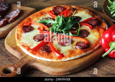 Hot hausgemachte Pizza mit Salami, paprica, Rucola auf hölzernen Tisch Stockfoto