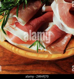 Italienische Prosciutto Crudo oder jamon mit Rosmarin auf Schneidebrett Stockfoto