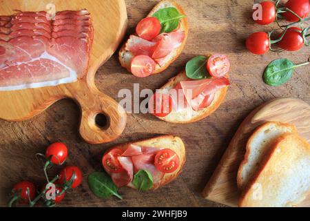 Bruschetta mit Schinken, Tomaten und grüne Spinat. Ansicht von oben Stockfoto