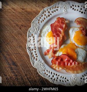 Frühstück, knusprigem Speck, Spiegelei und Brot. Sandwiches auf weiße Platte. Rustikale Tabelle. Ansicht von oben Stockfoto