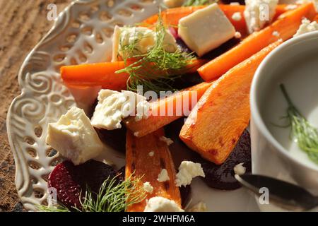 Gesunder gegrillter Rüben-, Karottensalat mit Käsefeta, Fenchel und griechischem Joghurt in kleinen Glasschalen auf dem rustikalen Holztisch, t Stockfoto