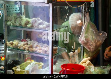 Ho-Chi-Minh-Stadt, Vietnam - 2. Februar 2024: Ein alter asiatischer Mann hinter dem Glas eines Stalls, der abends ein traditionelles vietnamesisches Gericht kocht. Dumpl Stockfoto