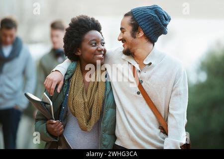Studenten, Universität und ein paar Freunde auf dem Campus mit Umarmung und Umarmung zusammen im Freien. College, Schulbildung und Vielfalt mit einem Happy Stockfoto