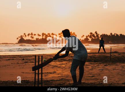 Junge spielt Cricket bei Sonnenuntergang am tropischen Strand in Sri Lanka Stockfoto