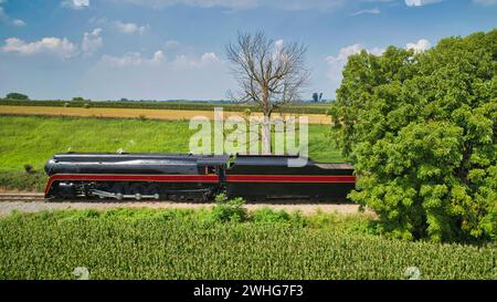 Seitliche Drohnenansicht einer antiken Dampflok, die sich nähert, Dampf bläst und durch die Landschaft fährt Stockfoto