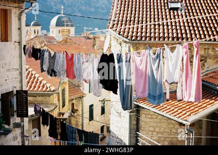 Bunte Leinen hängen an Seilen zwischen alten Häusern. Kotor, Montenegro Stockfoto