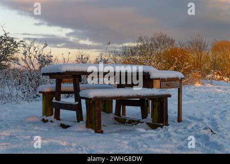 Schneebedeckte Holzbänke und Picknicktisch entlang des Flussufers in der Lurgies Gegend von Montrose an einem eisigen Abend im Januar. Stockfoto