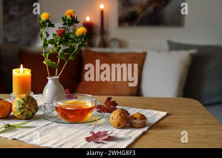 Teezeit im Herbst, Glasbecher, Kekse, Kürbisse und Kerzen auf einem Tisch in einem gemütlichen Zuhause, Kopierraum, ausgewählter Fokus Stockfoto