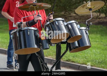 Mobiles Musikinstrument, Schlagzeug mit Schlagzeug und Zimbeln, gespielt von einer Frau in einer Marschkapelle, ausgewählter Fokus Stockfoto