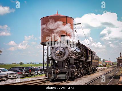 Blick auf eine Dampflokomotive, die an einem Wasserturm Wasser nimmt Stockfoto