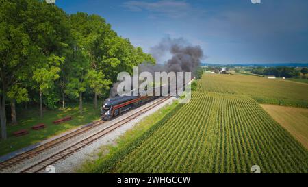 Drohnenansicht einer antiken Dampflok, Annäherung, Dampf blasen und Reisen auf dem Land Stockfoto