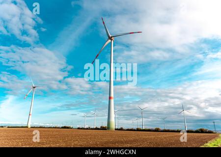 Windturbinen auf dem Feld gegen mit stimmungsvollem blauen Himmel und bewölktem Hintergrund. Gruppe von Windmühlen Stockfoto