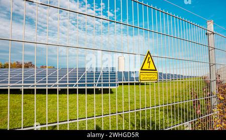 Warnschild „Gefahr Hochspannung“ am äußeren elektrischen Zaun. Solarkraftwerk. Stockfoto