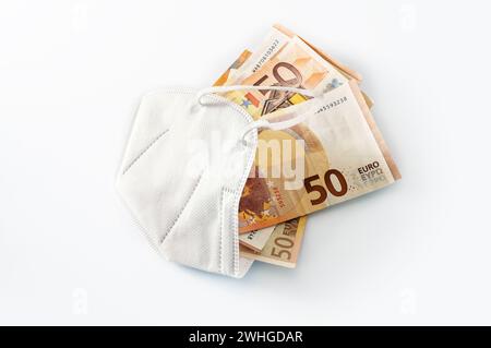 FFP2 medizinische Schutzmaske gegen Coronavirus gefüllt mit Euro-Banknoten, Konzept für steigende Kosten im Gesundheitswesen oder enr Stockfoto