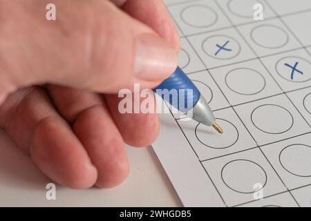 Hand mit blauem Stift, um Antwortkreuze auf einem Papierformular zu machen, Konzept für einen Business Application Test oder die Wahl bei einer Wahl, Co Stockfoto