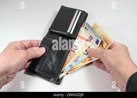 Hände, die verschiedene Euro-Banknoten aus einer schwarzen Ledergeldbörse nehmen, Geld- und Finanzkonzept, hellgrauer Hintergrund Stockfoto