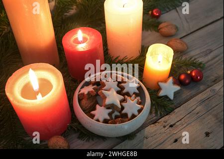 Zimtstern-Kekse zwischen leuchtenden Kerzen und Tannenzweigen, Dekoration in Adventszeit und Weihnachtszeit, Kopierraum, auswählen Stockfoto