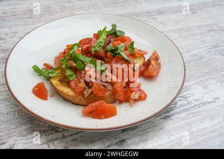 Bruschetta, geröstetes Brot mit Knoblauch und Olivenöl, serviert mit Tomatenwürfeln, Zwiebeln und Basilikum, beliebte italienische Vorspeise auf A Stockfoto