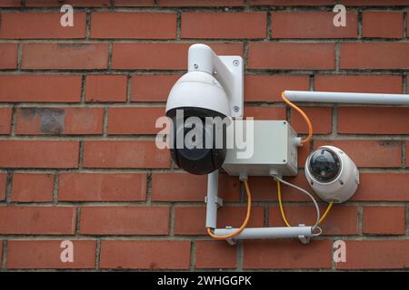 Überwachungskamerasystem auf einer roten Ziegelwand, moderne Sicherheitstechnik sammelt Videomaterial von umliegenden Vorfällen an p Stockfoto