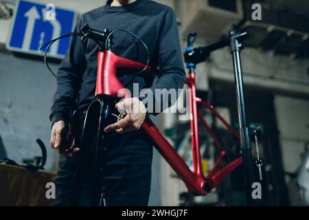 Mechaniker, der in der Werkstatt ein kundenspezifisches Fahrrad mit einem Schraubenschlüssel zusammenbaut. Stockfoto