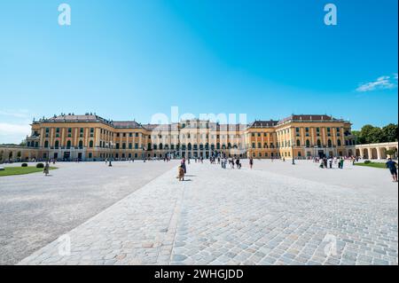 Wien, Österreich - 12. August 2022: Das Wiener Schloss schönbrunn erhebt sich über einem belebten Stadtplatz, während sich die Menschen unter dem Sommerhimmel versammeln und die Gr. Bestaunen Stockfoto