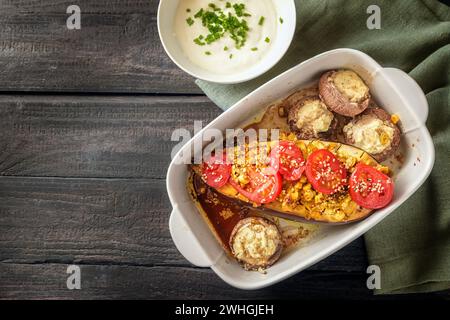 Gebackene Auberginen und Pilze mit Knoblauch, Ingwer, Zwiebeln, Tomaten und Sesam im Auflauf, serviert mit Joghurt auf einer Serviette Stockfoto