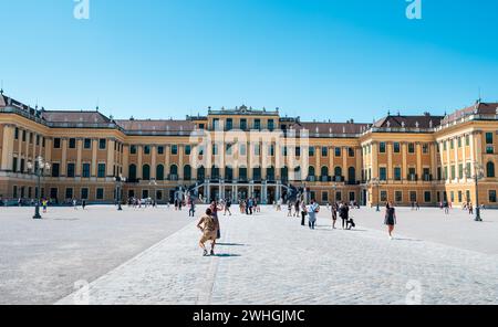 Wien, Österreich - 12. August 2022: Das Wiener Schloss schönbrunn erhebt sich über einem belebten Stadtplatz, während sich die Menschen unter dem Sommerhimmel versammeln und die Gr. Bestaunen Stockfoto