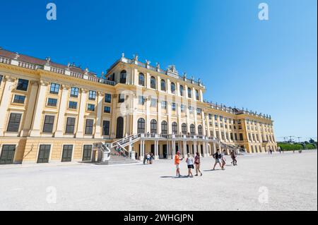 Wien, Österreich - 12. August 2022: Das Wiener Schloss schönbrunn erhebt sich über einem belebten Stadtplatz, während sich die Menschen unter dem Sommerhimmel versammeln und die Gr. Bestaunen Stockfoto