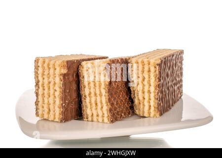 Drei süße Schokoladenscheiben auf einer weißen Keramikuntertasse, Makro, isoliert auf weißem Hintergrund. Stockfoto