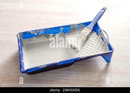 Blaues Farbtablett mit hellgrauem Lack und einem Pinsel auf einem Holztisch, Bastelkonzept zum Renovieren, Malen und selber machen Stockfoto