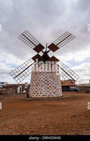 Eine traditionelle Windmühle mit Steinfuß und Holzklingen vor einem bewölkten Himmel in Valles de Ortega, Fuerteventura. Stockfoto