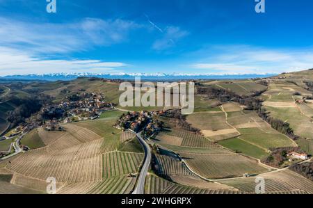 Die hügelige Landschaft im italienischen Piemont mit dem Dorf Barolo und schneebedeckten Bergen dahinter Stockfoto