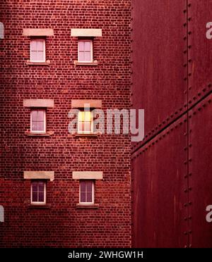 Ein helles rotes Backsteingebäude mit Fenstern Stockfoto