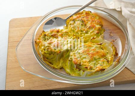 Gebackene Scheiben von Chinesisch- oder napa-Kohl in einem Glasauflauf auf einem hölzernen Küchenbrett, kreatives vegetarisches Gericht, Kopierraum, se Stockfoto