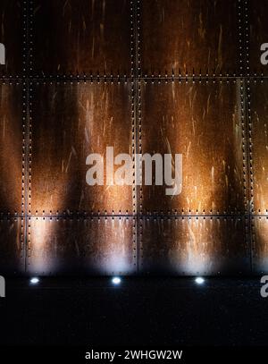Eine verrostete industrielle Metallwand, beleuchtet durch helle Lampen Stockfoto