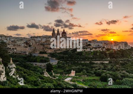 IL-Mellieha, Malta: Blick auf die Skyline der Stadt Mellieha bei Sonnenuntergang mit der Pariser Kirche auf einem Hügel Stockfoto