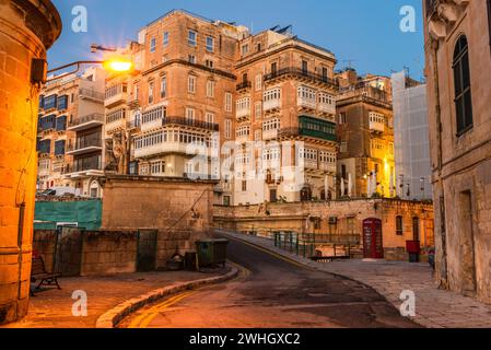 Valletta, Malta: Die traditionellen maltesischen Häuser mit Balkonen und Wänden von Valletta, die vor Sonnenaufgang beleuchtet sind Stockfoto