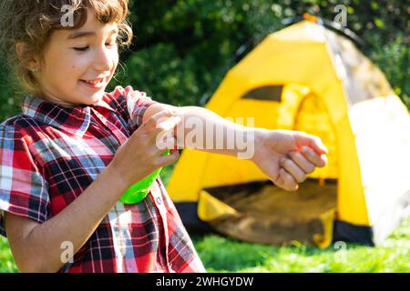 Das Mädchen sprüht Mückenspray auf die Haut in der Natur, die in ihre Hände und Füße beißt. Schutz vor Insektenbissen, abweisend sicher für Stockfoto