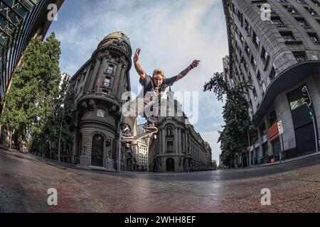 Skater, der eine ollie in der Innenstadt von Santiago an einem sonnigen Sommertag mit einem Weitwinkelobjektiv mit Blitz macht Stockfoto