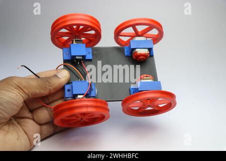 Basis eines Prototyps eines 3D-gedruckten Modellautos mit 3D-gedruckten Teilen, die in der Hand auf weißem Hintergrund gehalten werden Stockfoto