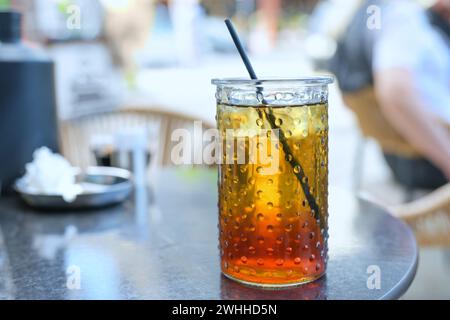 Erfrischender Eistee mit Zitronensirup und Trinkhalm in einem Glas in einem Straßencafé im Sommer, ausgewählter Fokus Stockfoto