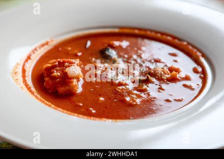Norwegischer Bacalao, ein gesalzener Kabeljau-Eintopf in einer roten Tomatensoße, wird in einer weißen Schüssel mit sichtbaren Fischstücken und einer Kräutergarnitur serviert. Stockfoto