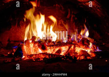 Helle Flammen steigen energetisch aus brennenden Holzstämmen auf. Stockfoto