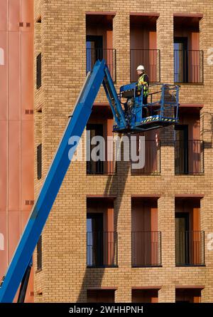 Scherenhub wird von Bauarbeitern für sicheren Zugang in der Höhe betätigt Stockfoto