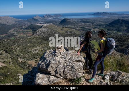 Wanderer, die Cucuia de Fartaritx mit der Bucht von Alcudia im Hintergrund aufsteigen Stockfoto