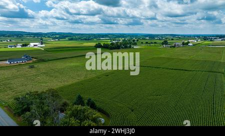 Riesige Aussicht aus der Vogelperspektive mit Einem Flickenteppich aus Feldfrüchten, Bauernhöfen, Einer Serpentinenstraße und üppigen Bäumen, die alle unter Einem Himmel voller flauschiger weißer Wolken liegen. Stockfoto