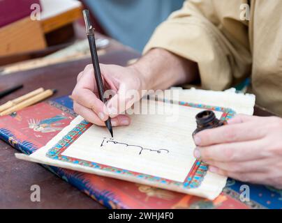 Mann, der mit einer Feder auf Pergamentpapier schreibt Stockfoto