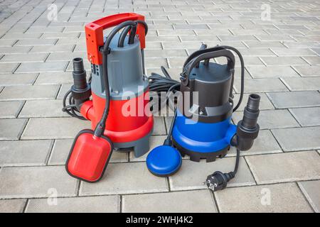 Zwei Haushalts-Tauchpumpen mit Kunststoffgehäusen auf Steinboden Stockfoto