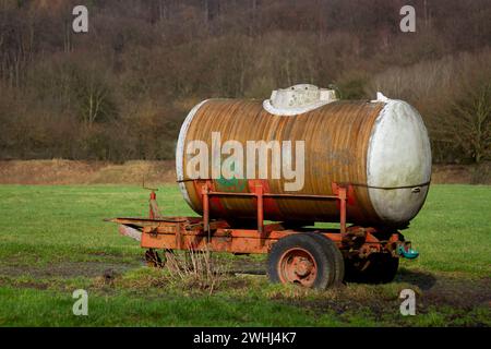 Tankwagen im Retro-Stil mit Holzrädern, die auf ländlichem Grasland geparkt sind Stockfoto