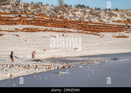 Fort Collins, CO, USA - 4. Februar 2024: Gruppe junger Menschen, die in einem Eisloch im Frozen Horsetooth Reservoir in Colorado f Stockfoto